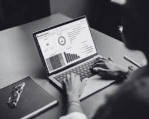 Une femme de dos utilisant l'outil de business intelligence MyReport. Elle est en train de naviguer sur l'interface de la solution et construire son propre tableau de bord.