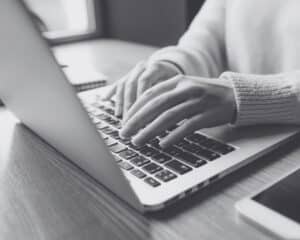 Une personne qui écrit sur son ordinateur en gros plan.