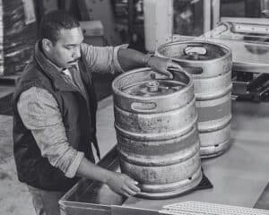 Photo d'une personne qui range des barils dans une usine agroalimentaire. Cette image illustre l'e-book sur la filière Sage X3 Agro.