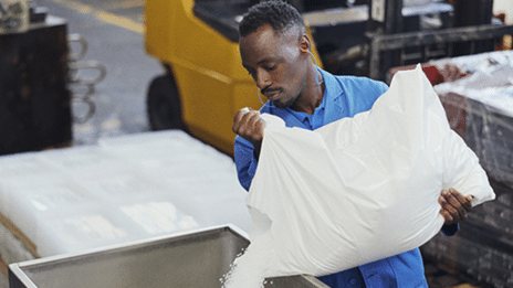 Illustration Sage X3 un homme travaille dans un entrepôt et verse un sac dans un contenant.