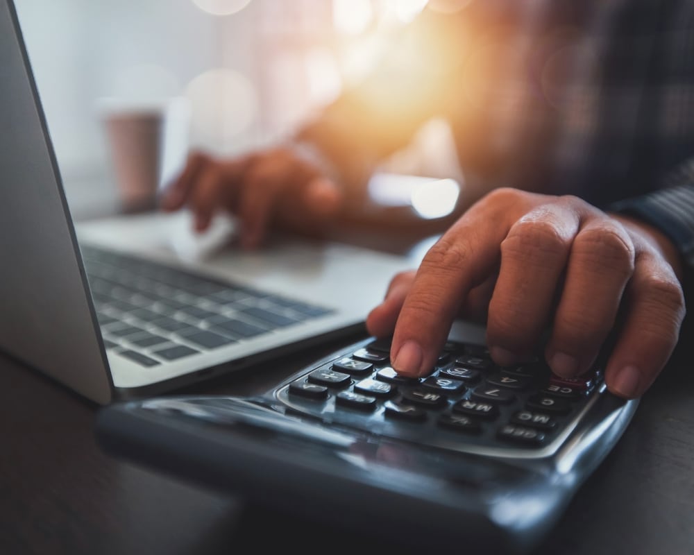 Image d'illustration pour la RFE. Une personne consultant sa facture sur son ordinateur avec à côté de lui une calculette.